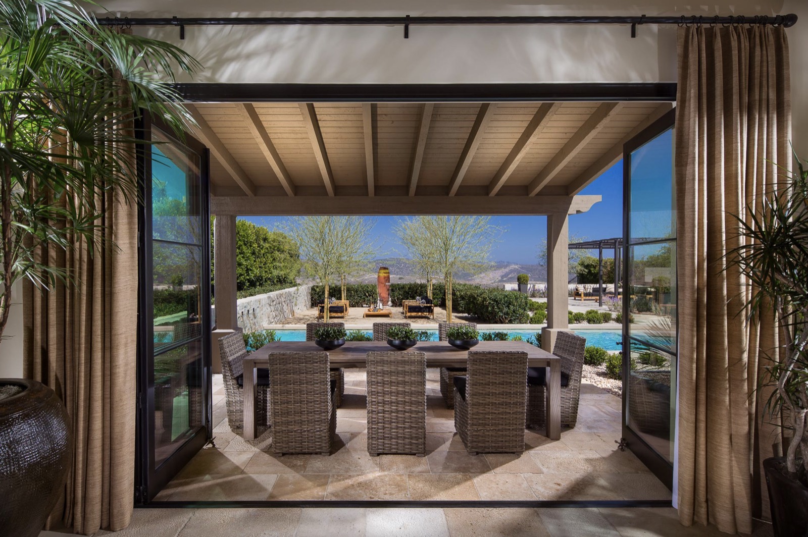 Bi‑folding doors framing an outdoor dining area and pool